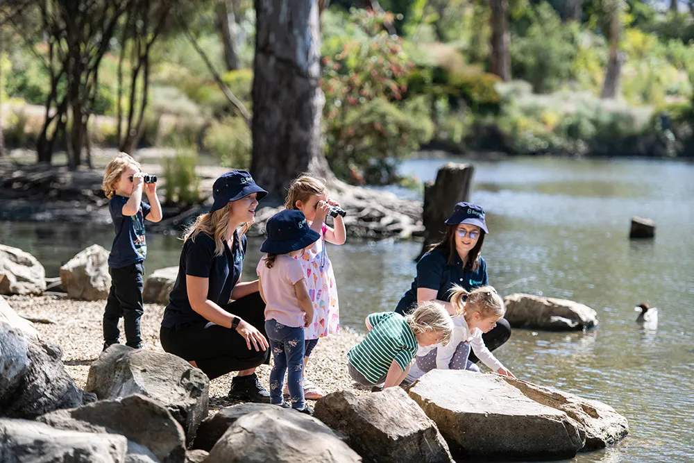 Children with educators exploring a natural outdoor environment.