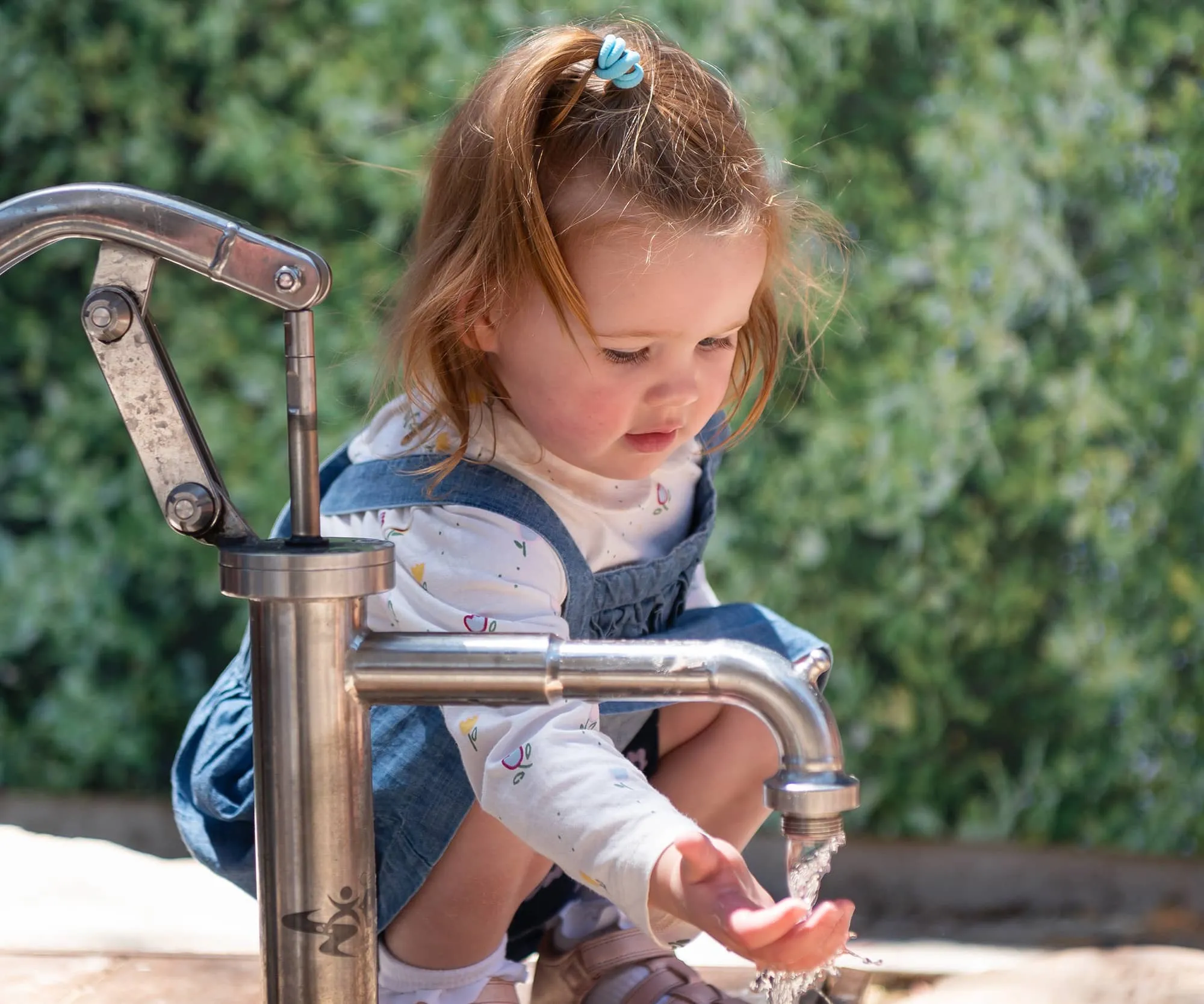 Child learning through natural water play outdoors at a Beyond Early Learning centre.